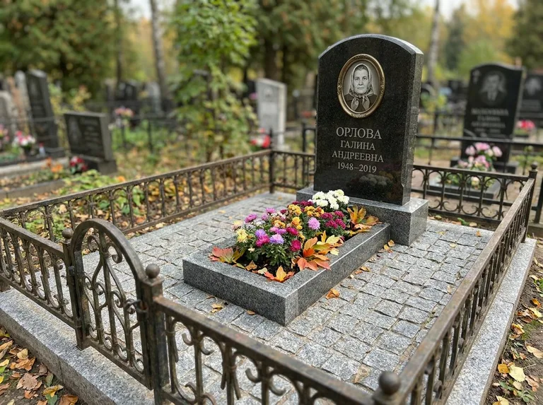 Благоустроенное захоронение с гранитной плиткой, оградой и цветником в Салехарде