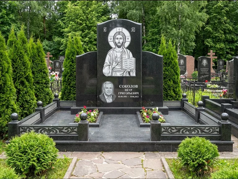 Памятник с гравировкой иконы: широкая горизонтальная лежачая плита-стела — икона в резной рамке-киоте, серая гравийная отсыпка с бордюром, работа «Богданова» в Салехарде