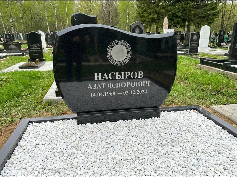 Мусульманский памятник: стела с волнообразным скошенным верхом — гравировка мечети под полумесяцем и звёздами, белая мраморная крошка с бордюром, работа «Насыров» в Салехарде