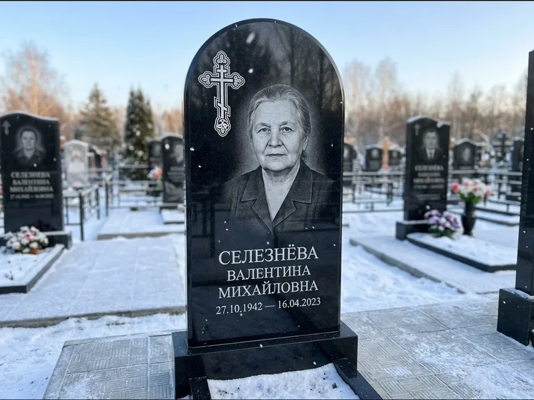 Памятник из чёрного гранита — массивная стела с крестом в лучах с крестом в лучах, работа «Одинцова» в Салехарде