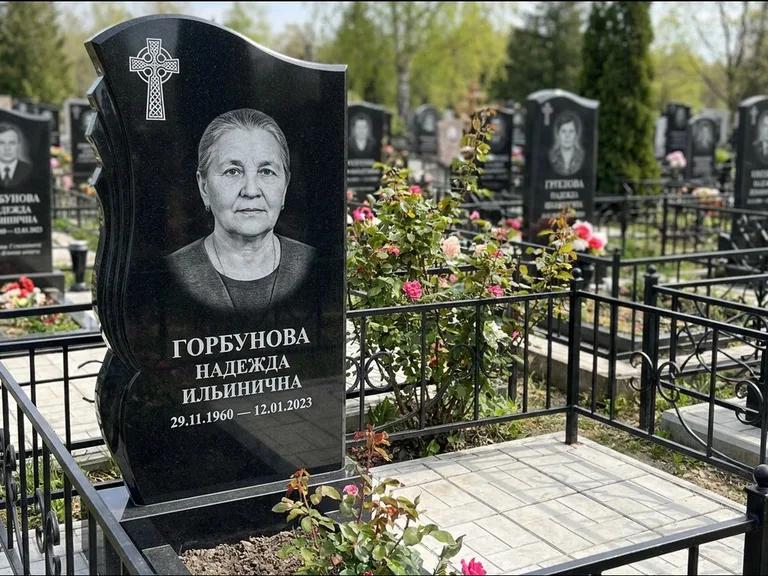 Памятник из чёрного гранита — высокий обелиск с кельтским крестом, работа «Одинцова» в Салехарде