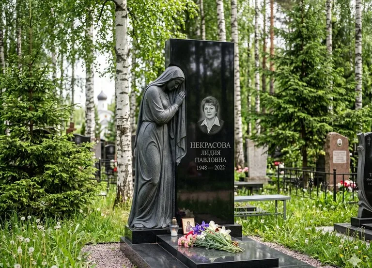 Гранитная фигура скорбящего мужчины у чёрной стелы в Салехарде